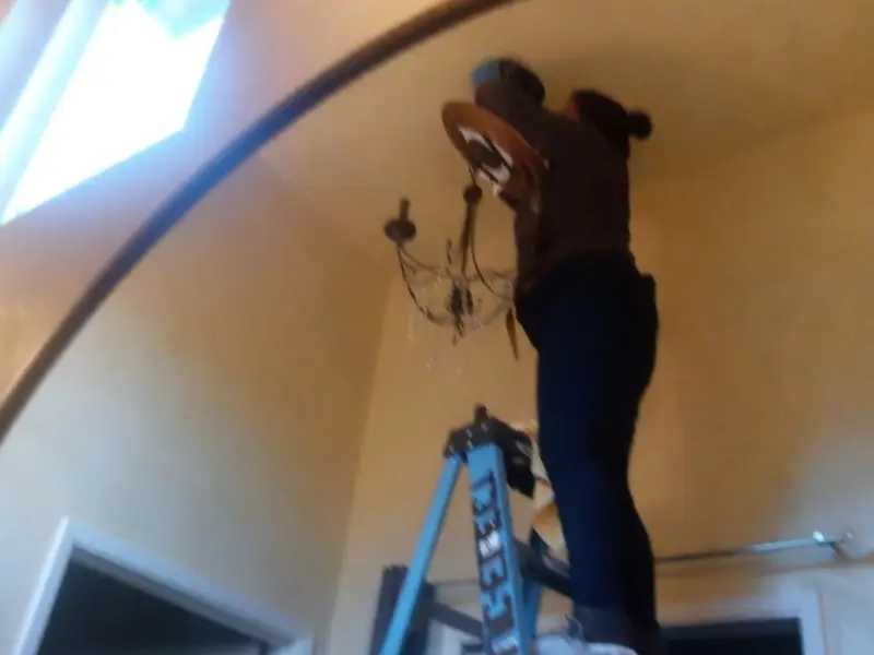 Electrician installing a chandelier in a Montague residence